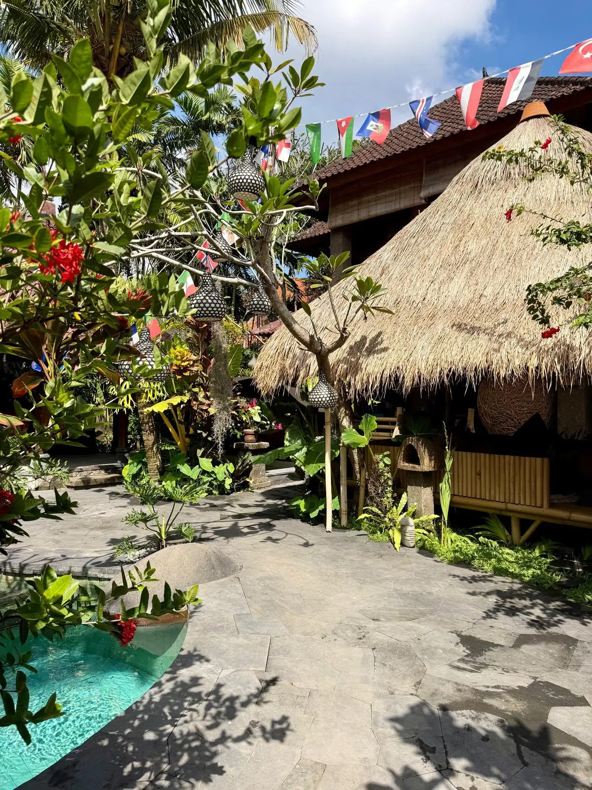 The Lazy Rabbit Hostel garden in Ubud — pool, thatched gazebo and flags from every guest's country